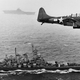 A U.S. Navy Douglas SBD-5 Dauntless of bombing squadron VB-16 flies an antisubmarine patrol low over the battleship USS Washington (BB-56) en route to the invasion of the Gilbert Islands, 12 November 1943. Image via U.S. Navy National Museum of Naval Aviation/Wikimedia.
